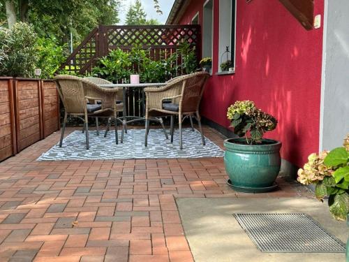 a patio with a table and chairs and a red wall at Ferienwohnung Annette Mieth in Weitenhagen