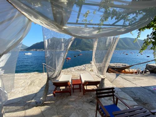 a beach with chairs and a table and the water at Boka Bay Beach House in Dražin Vrt