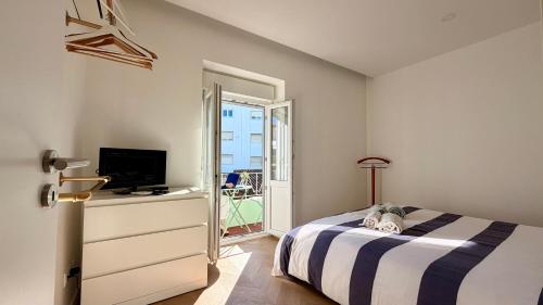 a bedroom with a bed and a tv and a window at Design no centro histórico a 30 min Lisboa in Torres Vedras