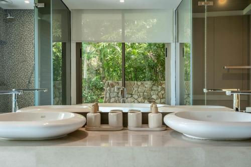 a bathroom with two sinks and a large mirror at Villa Skyfall Thailand Phuket in Panwa Beach