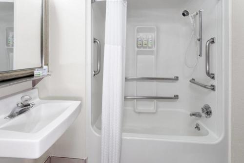 a white bathroom with a sink and a shower at Baymont by Wyndham Green Bay in Green Bay