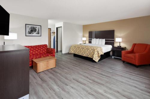 a hotel room with a bed and a red couch at Baymont by Wyndham Green Bay in Green Bay