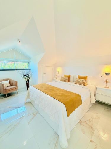 a white bedroom with a large bed and a couch at Refúgio do Vale Verde in Ponta do Sol