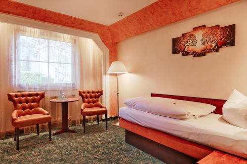 ein Hotelzimmer mit Bett, Tisch und Stühlen in der Unterkunft Hotel Aragon in Ahrensfelde