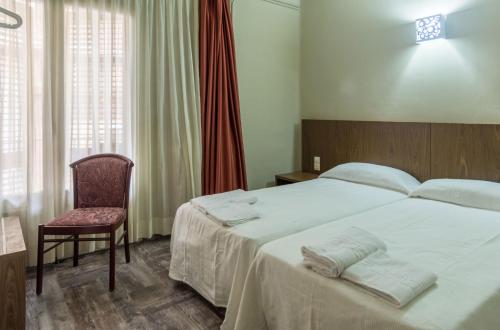 a bedroom with a large white bed and a chair at Hostal Sant Miquel in Balaguer