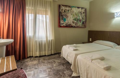 a hotel room with two beds and a sink at Hostal Sant Miquel in Balaguer