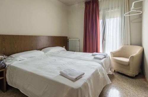 a bedroom with a large white bed and a chair at Hostal Sant Miquel in Balaguer