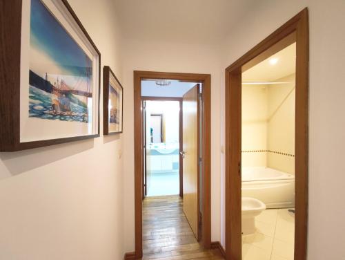 a hallway with a bathroom with a toilet and a tub at Colinas do Cruzeiro Residence Odivelas in Odivelas