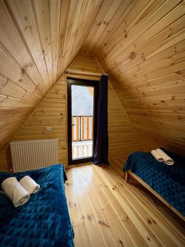 two beds in a wooden room with a window at Kedari Borjomi Cottage in Borjomi