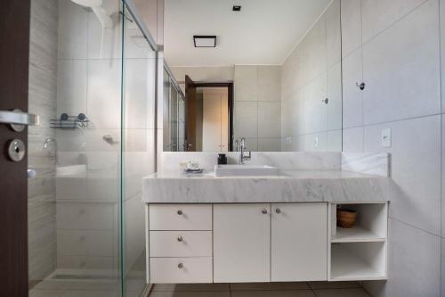 a white bathroom with a sink and a shower at Citizen Bueno by Marzani Host in Goiânia
