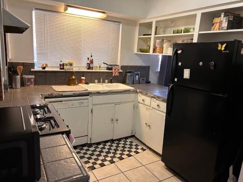 a kitchen with white cabinets and a black refrigerator at Key to Austin Artistry in Austin