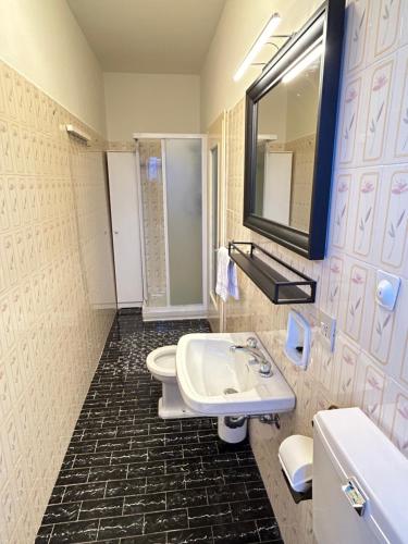 a bathroom with a sink and a toilet and a mirror at Discovering Apartment Pulicchio in Abetone