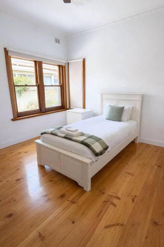a white bedroom with a bed and a window at 2BR Beachfront Escape in Largs North in Semaphore