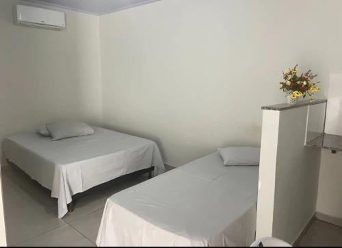 a room with two beds and a table with flowers on it at Apart hotel in Três Marias