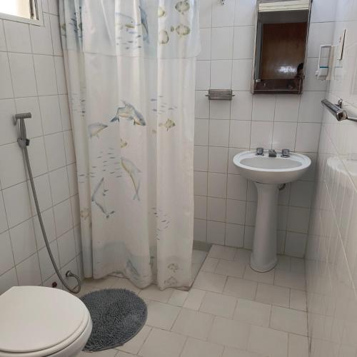 a bathroom with a shower curtain with a toilet and a sink at Casa VLG 5 pax in Las Grutas