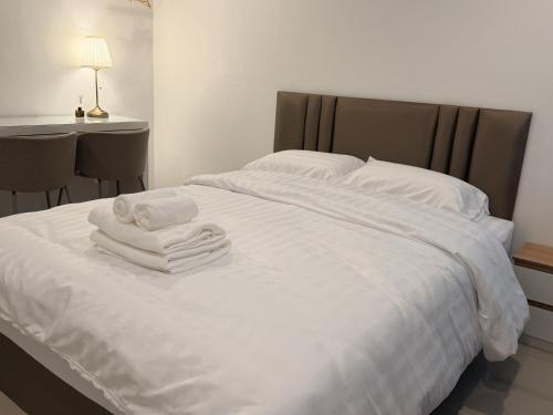 a white bed with towels on top of it at ดิโอโซน THE Ozone in Ban Bung Sanan