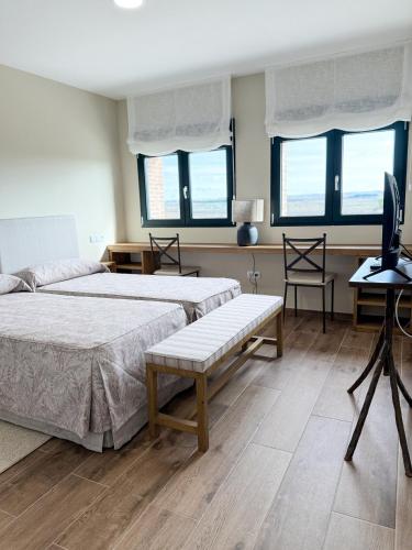 a bedroom with two beds and a tv and a desk at Alojamiento rural Solterra in Roa