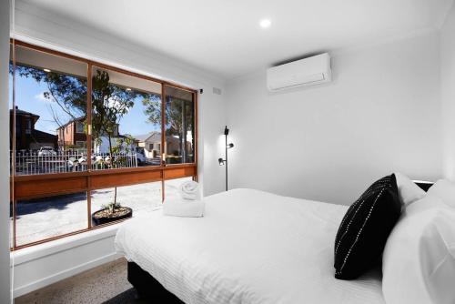 a bedroom with a white bed and a large window at Sunshine Family Sophistication in Albion
