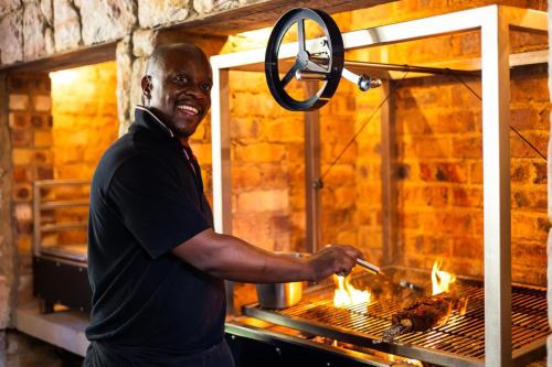 a man is cooking food in an oven at Afrique Boutique Hotel O.R. Tambo in Boksburg