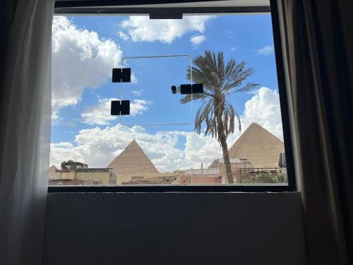 a window with a view of pyramids and a palm tree at Calm Pyramids View Villa in Cairo