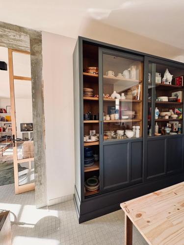 a black cabinet with dishes in it in a room at MAISON BO TERRA - Chambres et table d'hôtes - Massif des Écrins in Valbonnais