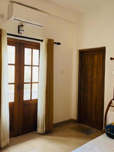 a room with a door and a window and a bed at New Arverne Villa Kandy in Kandy