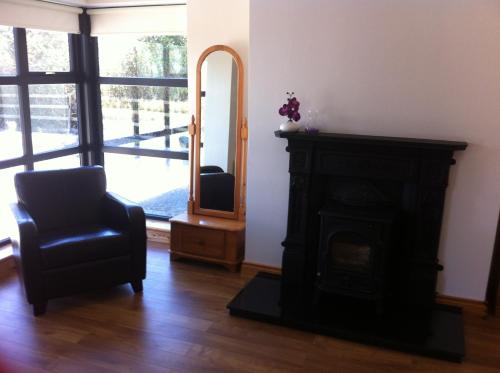 a living room with a fireplace and a chair and a mirror at Kilmore Quay Castleview 1 - 5 Bedroom House in Kilmore Quay