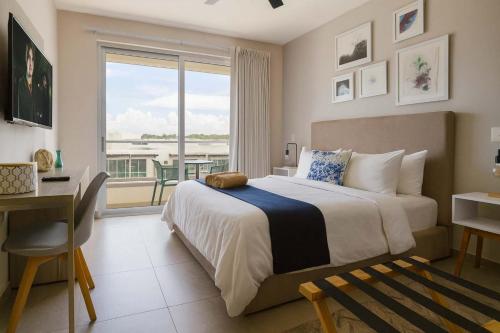 a bedroom with a bed and a desk and a window at Steps from 5th Ave with Rooftop Pool Gym & Cinema in Playa del Carmen