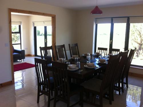 - une salle à manger avec une table, des chaises et des fenêtres dans l'établissement Kilmore Quay Castleview 1 - 5 Bedroom House, à Kilmore Quay