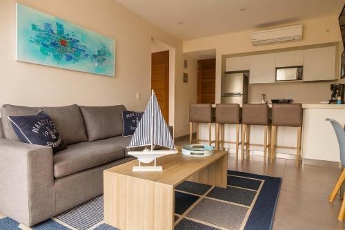 a living room with a couch and a table and a kitchen at Steps from 5th Ave with Rooftop Pool Gym & Cinema in Playa del Carmen