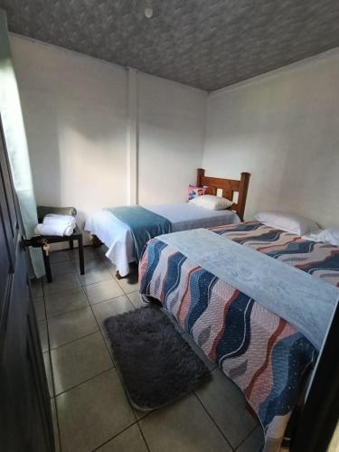 a bedroom with two beds and a chair in it at Casa Mariposa Full Accommodation in Sabalito