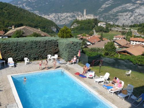 a group of people sitting around a swimming pool at Albergo Drena in Drena