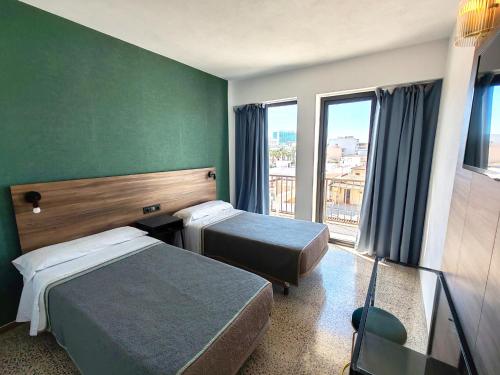 a hotel room with two beds and a window at Hotel OCTOPUS in Can Picafort