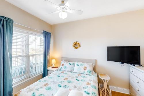 a bedroom with a bed and a flat screen tv at Oceanfront, dog-friendly condo with ocean view, pool & central AC in Hatteras