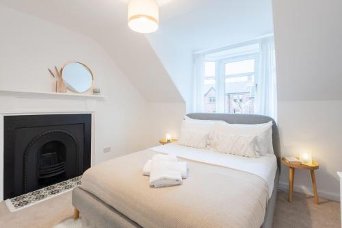 a white bedroom with a bed with a fireplace at Glengate - Traditional home in Kirriemuir in Kirriemuir