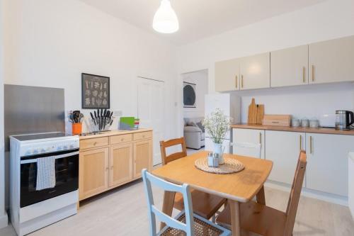 a kitchen with a wooden table and a kitchen with white cabinets at Glengate - Traditional home in Kirriemuir in Kirriemuir
