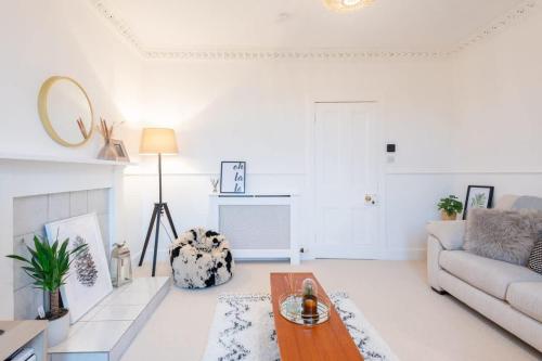 a white living room with a couch and a table at Glengate - Traditional home in Kirriemuir in Kirriemuir