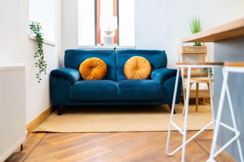 a blue couch with two orange pillows on it at The Church Front in Montrose