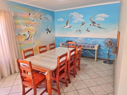 a dining room with a table and birds on the wall at Vitamiene-See Hartenbos in Hartenbos