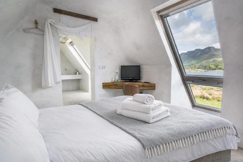 a white bedroom with a bed with a window at Plockton Shoreside House in Plockton