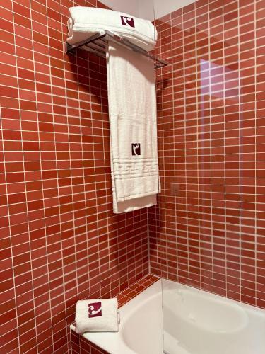a bathroom with brown tiled walls and a sink and towels at Casa Rural Solterra in Roa