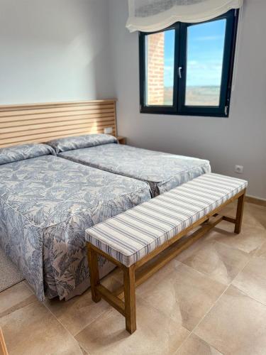 a bedroom with two beds with a bench on it at Casa Rural Solterra in Roa
