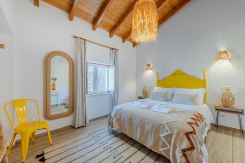 a bedroom with a bed and a mirror and a chair at Casa do Arlindo in São Bartolomeu de Messines