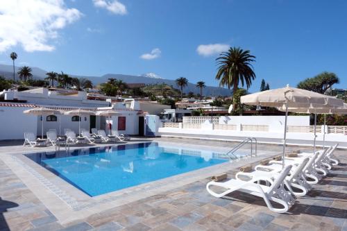 a swimming pool with lounge chairs and an umbrella at Muthu La Perla Tenerife in Puerto de la Cruz