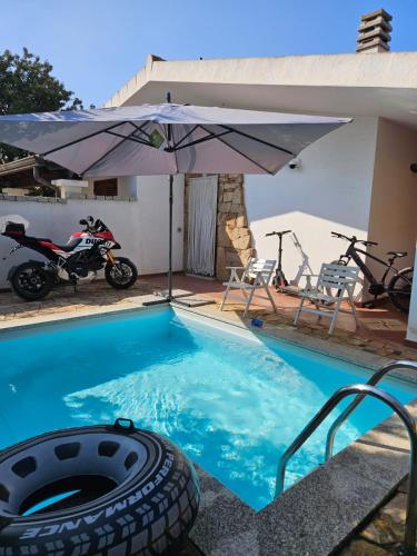 a motorcycle and an umbrella next to a swimming pool at Da Anna Casa Vacanza Al Mare in Santa Lucia