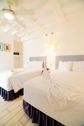 two beds in a bedroom with white walls and wood floors at Hotel Casa Turquesa in Flores