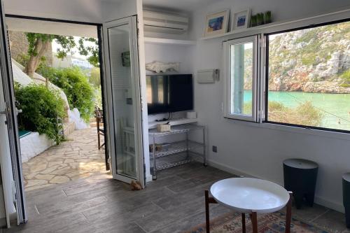 a room with a sliding glass door and a television at Beachfront Apartment in Calan Porter Menorca in Cala en Porter