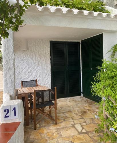 a table and a chair in front of a house at Beachfront Apartment in Calan Porter Menorca in Cala en Porter