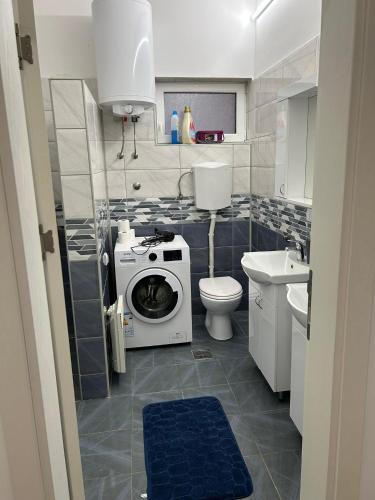 a bathroom with a washing machine and a toilet at Apartmani Centar in Sivac