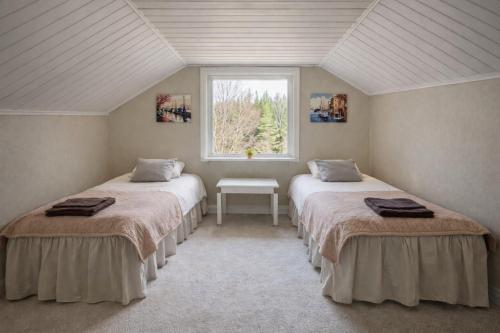 two beds in a room with a window at Lilla Röda Huset. in Sjötofta